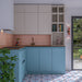 Contemporary kitchen featuring Normandie Blush Pink rustic effect gloss wall tiles in 7.5cm x 15cm. Gloss pink brick tiles create a soft, colourful splashback, beautifully complemented by pale blue cabinetry and patterned floor tiles for a playful yet elegant kitchen design.
