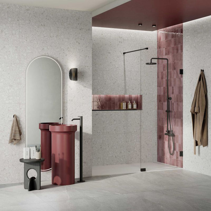 Contemporary bathroom featuring Noventa Blanco 3D Terrazzo 60x120cm porcelain wall tiles, showcasing a white terrazzo effect with textured 3D stone chips, paired with a burgundy feature basin, pink gloss shower tiles, black fittings and a frameless walk-in shower.