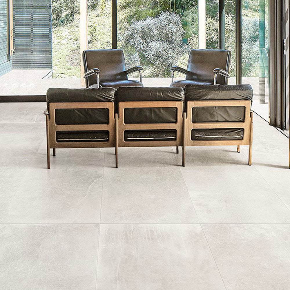 Living room featuring Obsidian Stone Silk 60x60cm stone-effect porcelain floor tiles in soft light grey tones, styled with modern leather seating, large glazing and minimalist contemporary interiors filled with natural light.