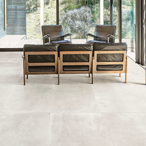 Living room featuring Obsidian Stone Silk 60x60cm stone-effect porcelain floor tiles in soft light grey tones, styled with modern leather seating, large glazing and minimalist contemporary interiors filled with natural light.