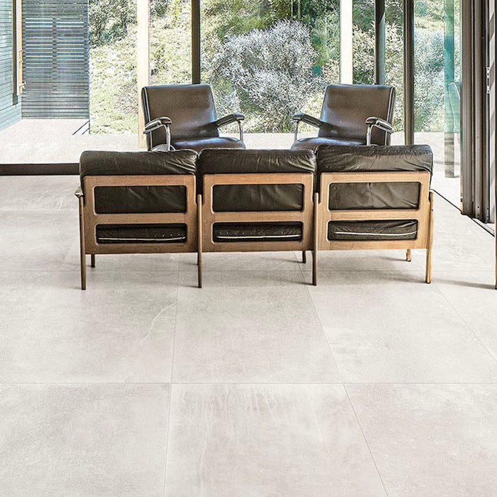 Living room featuring Obsidian Stone Silk 60x60cm stone-effect porcelain floor tiles in soft light grey tones, styled with modern leather seating, large glazing and minimalist contemporary interiors filled with natural light.