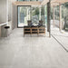 Living room featuring Obsidian Stone Silver 30x60cm stone-effect porcelain floor tiles in soft silver-grey tones, styled with modern leather seating, large glazing and contemporary open-plan interiors filled with natural light.