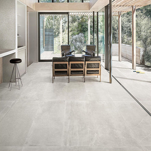 Living room featuring Obsidian Stone Silver 60x60cm stone-effect porcelain floor tiles in soft silver-grey tones, styled with modern leather seating, large glazing and contemporary open-plan interiors filled with natural light.