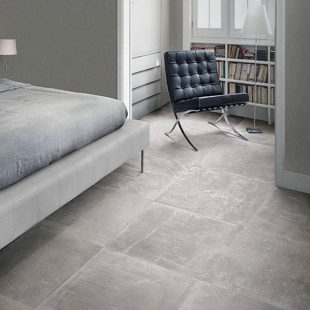 Bedroom featuring Obsidian Stone Titanium 60x60cm stone-effect porcelain floor tiles in mid-grey tones, styled with soft neutral interiors, modern furnishings, chrome accents and minimalist contemporary décor.