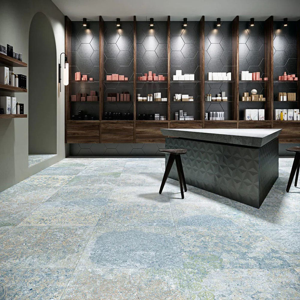 Interior featuring Boheme Ocean Blue 60 × 60cm patterned floor tiles, blending soft blue and muted tones with a worn, decorative effect. Ideal for adding character to contemporary spaces such as retail interiors, kitchens, or open-plan living areas.