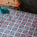 Interior workspace featuring Europa Vienna 20x20cm Victorian Moroccan style floor tiles in blue, pink and white tones, styled with a wooden desk, green chair and dark wall tiles in a contemporary office setting.