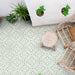 Overhead view of Europa Trondheim Sage Green 20x20cm Victorian Moroccan style floor tiles in sage green and cream tones, forming an intricate geometric pattern, styled with rattan furniture and potted plants in a bright interior setting.