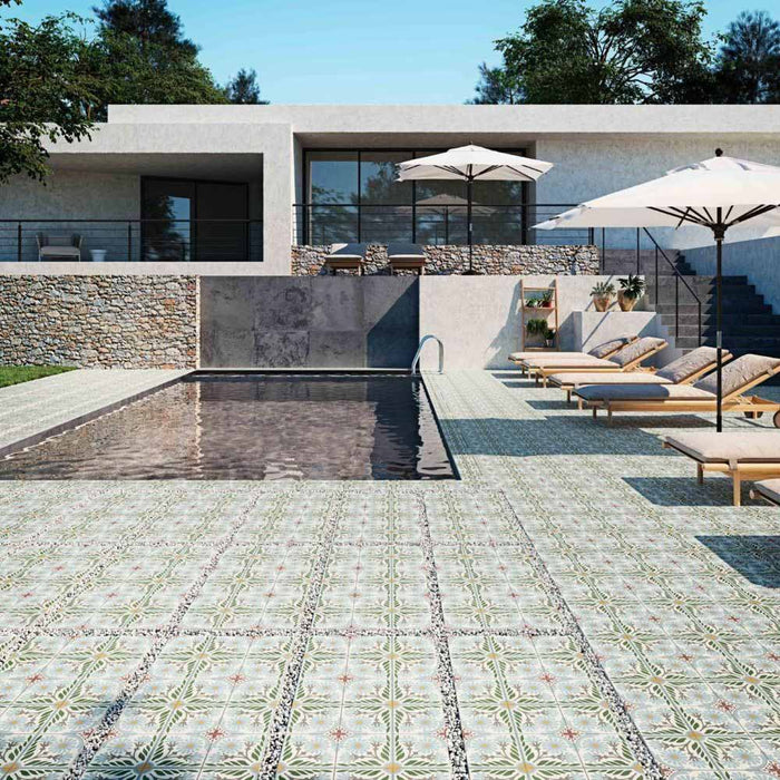 Modern outdoor pool area featuring Palma Olbia 2cm patterned outdoor slabs 50 × 100cm, showcasing a faded Mediterranean-inspired design in soft green and neutral tones, paired with sun loungers and contemporary architecture.