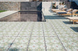Modern outdoor pool area featuring Palma Olbia 2cm patterned outdoor slabs 50 × 100cm, showcasing a faded Mediterranean-inspired design in soft green and neutral tones, paired with sun loungers and contemporary architecture.