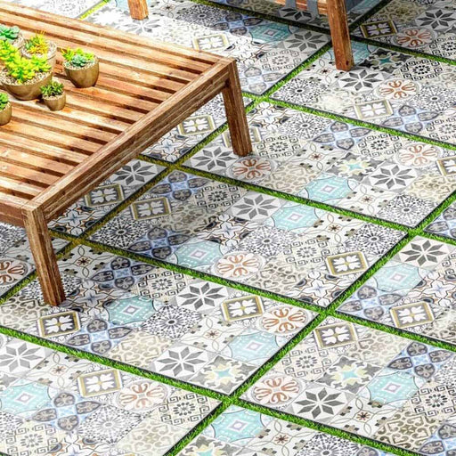 Outdoor seating area featuring Palma Patchwork 2cm patterned outdoor slabs 50 × 100cm, showcasing a mixed patchwork-inspired design in soft blue, grey, beige, and cream tones, paired with natural wood garden furniture.