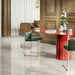 Living room featuring Paradis Marble Avorio Ivory stone marble effect porcelain wall and floor tiles in a 30cm x 60cm format, showcasing soft ivory, cream and light grey veining inspired by natural marble, paired with warm wood panelling, a bold red statement table, green upholstered dining chairs and contemporary furnishings for an elegant, design-led interior.