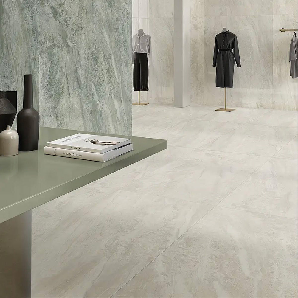 Retail showroom featuring Paradis Marble Beige stone marble effect porcelain wall and floor tiles in a 30cm x 60cm format, showcasing warm beige, ivory and soft cream veining inspired by natural marble, paired with minimalist display furniture, contemporary clothing rails and a bright, modern commercial interior for a refined, luxurious finish.