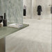 Retail showroom featuring Paradis Marble Beige stone marble effect porcelain wall and floor tiles in a 30cm x 60cm format, showcasing warm beige, ivory and soft cream veining inspired by natural marble, paired with minimalist display furniture, contemporary clothing rails and a bright, modern commercial interior for a refined, luxurious finish.