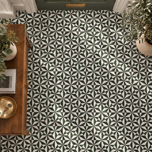 Hallway featuring Plaza Emerald Green & Carrara White 18.7x21.6cm hexagon floor tiles, creating a striking green and white geometric star pattern, paired with a dark green front door, wooden furniture and natural greenery.