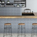 Restaurant interior featuring Iris Blue Victorian Moroccan-style 20×20cm porcelain tiles, used on bar fronts and walls to showcase a soft blue and cream geometric pattern, paired with wooden countertops, metal bar stools, and contemporary shelving.
