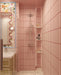 Bathroom interior featuring Rippled Brick Base Stony Pink 5 × 20cm matt ceramic wall tiles, laid vertically with fine linear detail, paired with a glass shower enclosure, terrazzo-effect flooring, and a playful, colour-led vanity area.