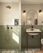 Bathroom featuring Rippled Brick Base Tansy Green Matt 5cm x 20cm wall tiles, laid vertically around the shower and basin, paired with patterned floor tiles, bronze fixtures and an arched mirror.