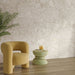 Living room interior featuring Contract Pebble Rock Avorio 60x120cm terrazzo effect porcelain wall tiles, styled with a curved mustard armchair, wooden flooring, a sculptural side table, and greenery for a warm, contemporary finish.