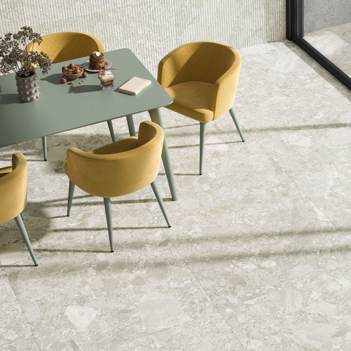 Dining area featuring Contract Pebble Rock Blanca 60x120cm terrazzo effect porcelain floor tiles, styled with a green table, mustard chairs, textured wall tiles, and large sliding glass doors for a light, open feel.