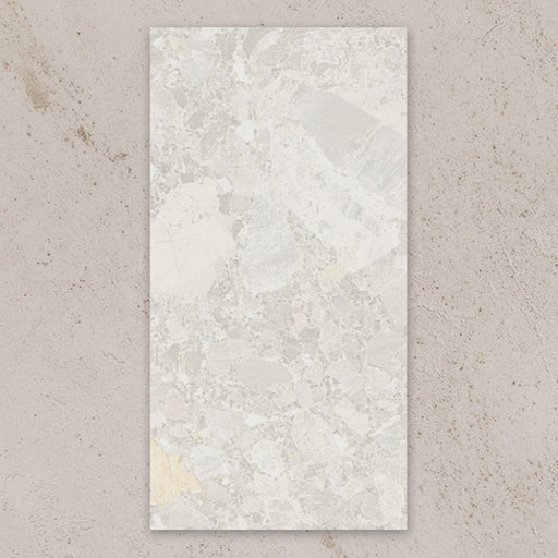 Single tile view of Contract Pebble Rock Blanca 60x120cm terrazzo effect porcelain tile, showcasing soft white and beige tones with varied stone fragments and a natural, blended surface pattern.