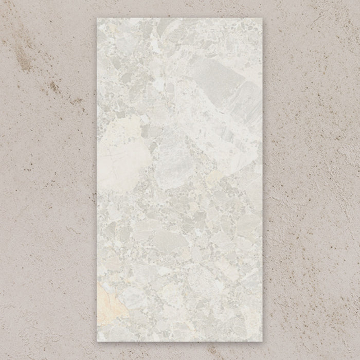 Single tile view of Contract Pebble Rock Blanca 60x120cm terrazzo effect porcelain tile, showcasing soft white and beige tones with varied stone fragments and a natural, blended surface pattern.