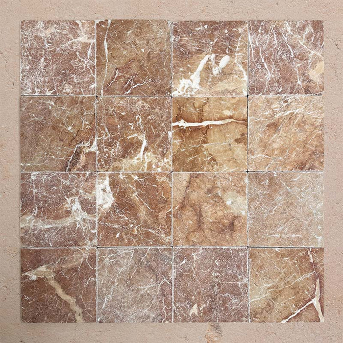 Group of Fitzrovia Rosso 15.2x15.2cm tumbled natural marble tiles arranged in a square layout, showcasing warm terracotta tones, varied veining, tonal variation, and a softly aged, textured finish.