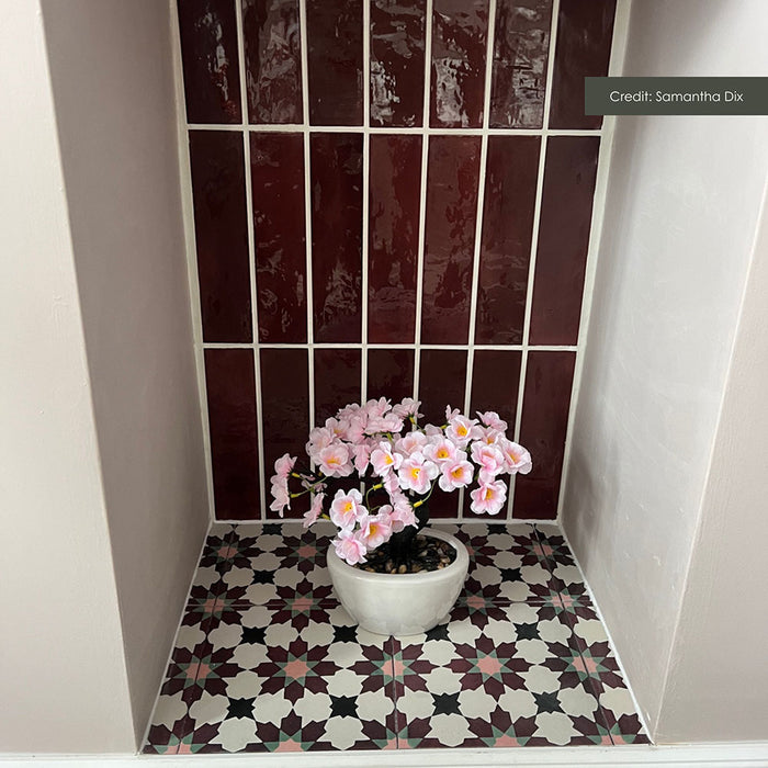 Recessed wall niche featuring Mamounia Vino 20 × 20cm Moroccan-style wall and floor tiles with a bold geometric pattern, paired with deep red gloss brick tiles and styled with a potted floral arrangement.
