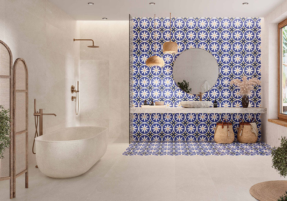 Bathroom featuring Santillana Blue and Yellow patterned wall and floor tiles, showcasing a bold Mediterranean-inspired floral geometric design in vibrant cobalt blue, warm yellow and crisp white tones, paired with a floating stone vanity, round mirror, woven pendant lights, natural baskets and soft neutral finishes for a bright, characterful interior.