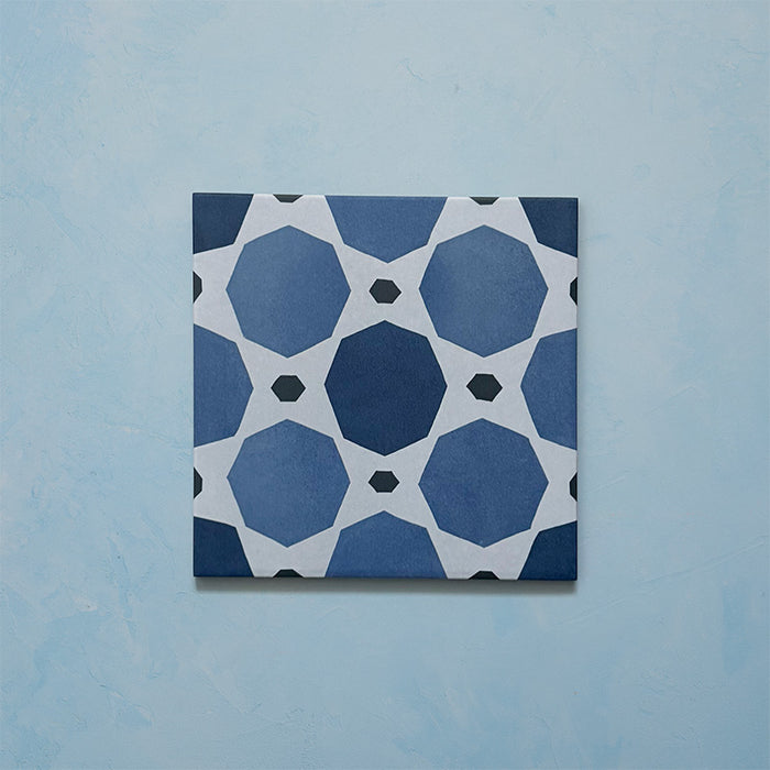 Single tile from the Carnaby Sapphire Victorian-style collection, 20x20cm porcelain wall and floor tile, featuring a bold blue geometric octagon pattern with white connecting lines and small charcoal accents.