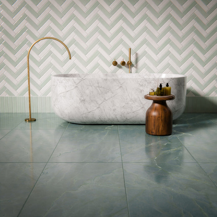 Bathroom setting featuring Madison White and Mint Green 6x24.6cm brick wall tiles in a herringbone layout, creating a soft, layered look, paired with a marble bath, sage floor tiles and brushed brass fittings.