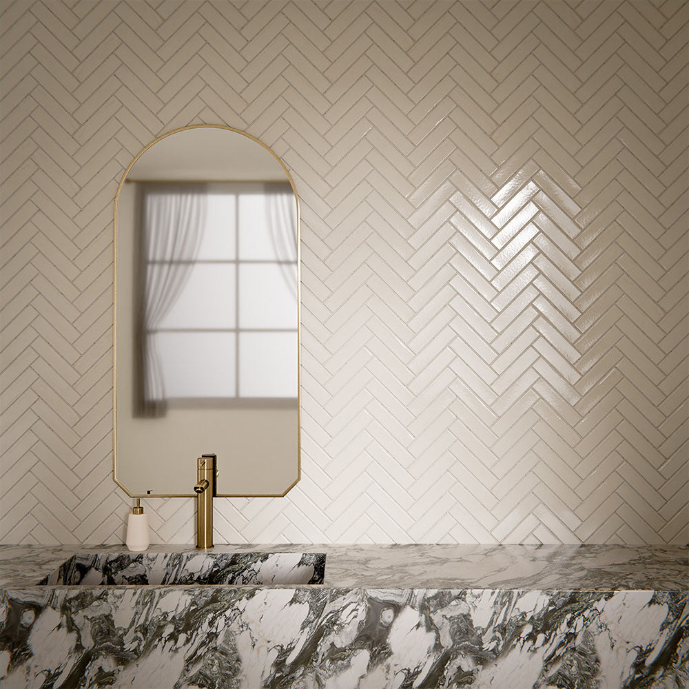 Bathroom interior featuring Play White Brick rectified wall and floor tiles in 5x20cm format, installed in a classic herringbone pattern, styled with a marble vanity and brushed brass fittings for a clean, contemporary finish.