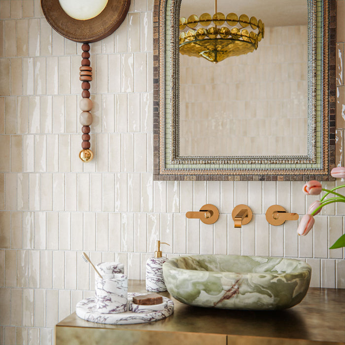 Bathroom featuring Atlas Canvas Mini Brick 5x15cm gloss wall tiles, installed in a vertical layout, showcasing soft neutral tones, paired with statement mirrors, brass fittings, and a warm, design-led interior setting.