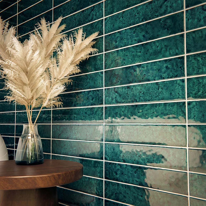 Bathroom interior featuring Malaga Amun Blue Brick gloss wall tiles in 6.5x32.8cm format, installed horizontally around a freestanding bath, showcasing rich blue tonal variation with brushed brass tap and neutral floor tiles.