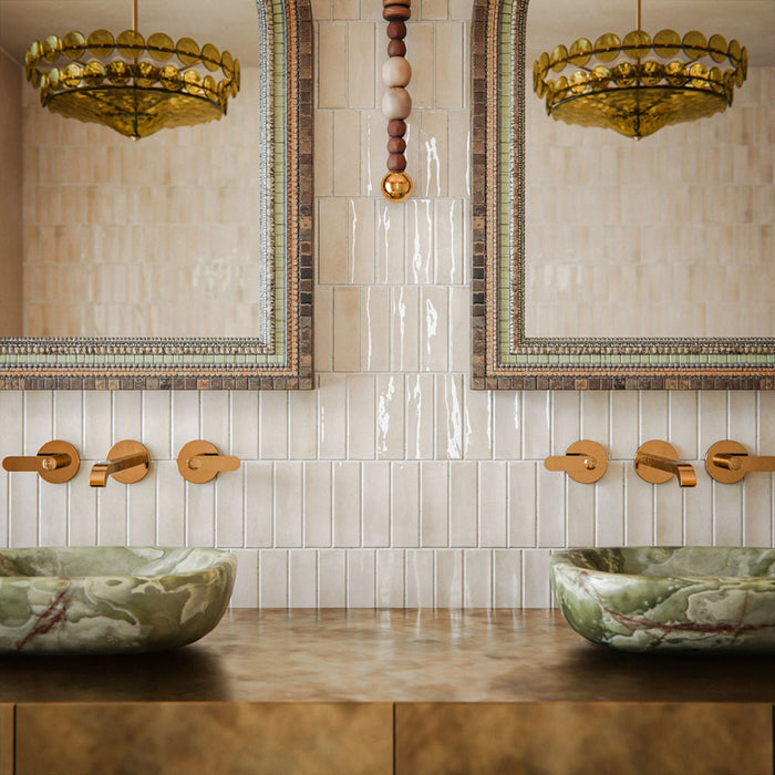 Bathroom featuring Atlas Canvas Mini Brick 5x15cm gloss wall tiles, installed in a vertical layout, showcasing soft neutral tones, paired with statement mirrors, brass fittings, and a warm, design-led interior setting.