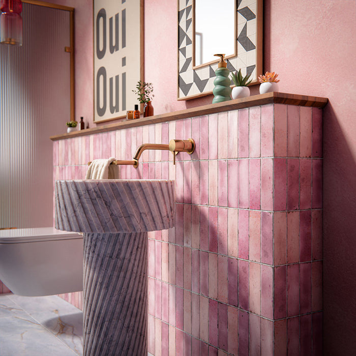 Bathroom setting featuring Fusion Bricks Coral Pink 6.5x20cm brick wall tiles, showcasing soft tonal variation, paired with a fluted marble basin, brass fittings and warm pink walls for a refined, design-led finish.