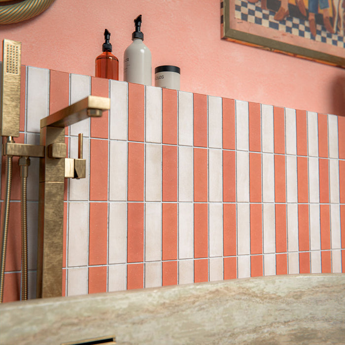Bathroom setting featuring Atlas Canvas and Atlas Cotto Mini Brick 5x15cm matt wall and floor tiles, laid in a striped layout, showcasing warm neutral and terracotta tones, paired with a freestanding stone bath and brass fittings.