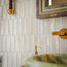 Bathroom featuring Atlas Canvas Mini Brick 5x15cm gloss wall tiles, installed in a vertical layout, showcasing soft neutral tones, paired with statement mirrors, brass fittings, and a warm, design-led interior setting.
