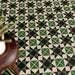 Close-up of Maison Green Decor Victorian patterned 20x20cm ceramic floor tiles in green, black and white geometric design.