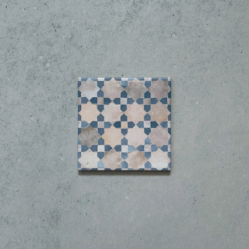 Single Bedouin Mequinez Blue Moroccan-style ceramic tile measuring 15x15cm, featuring a soft geometric pattern in shades of blue, cream, and taupe with a hand-painted, weathered finish on a neutral background.