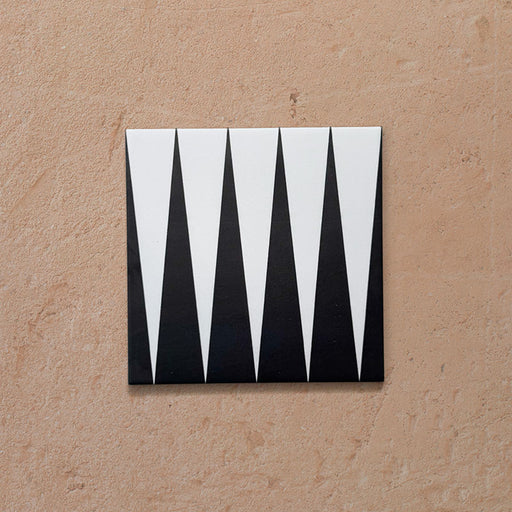Single Alhambra Tavla 20x20cm Moroccan tile featuring a bold black and white triangular geometric design on a matte surface, displayed against a neutral textured background.