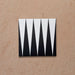 Single Alhambra Tavla 20x20cm Moroccan tile featuring a bold black and white triangular geometric design on a matte surface, displayed against a neutral textured background.
