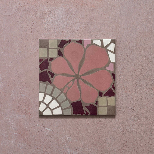 Single Bloom Rose Pink 20x20cm Moroccan-style ceramic tile featuring a floral pattern in blush pink, burgundy, taupe, and white tones, shown against a pink textured background in a close-up view.
