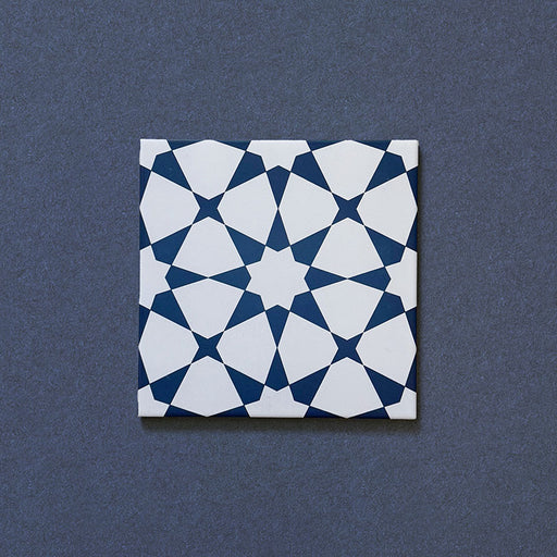 Close-up of Agraba Navy 20x20cm Moroccan-style ceramic tile featuring a bold geometric star pattern in deep navy blue and white on a textured dark background.