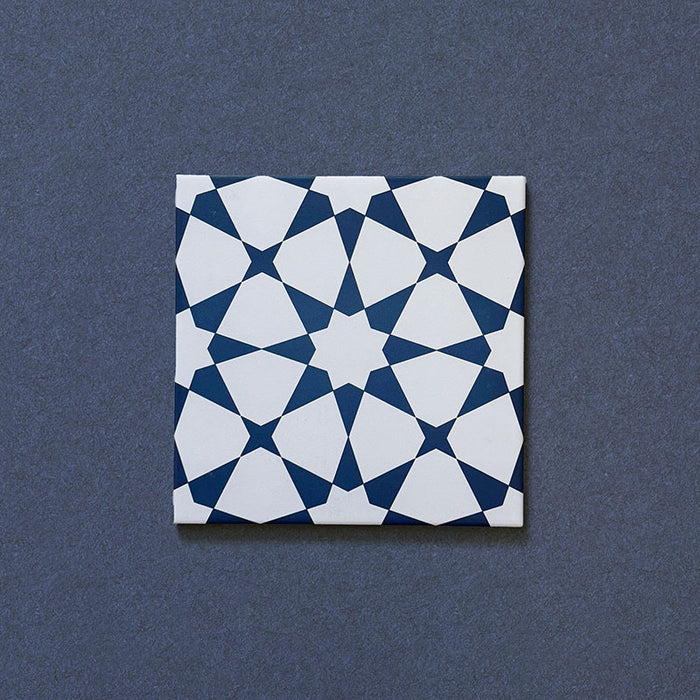 Close-up of Agraba Navy 20x20cm Moroccan-style ceramic tile featuring a bold geometric star pattern in deep navy blue and white on a textured dark background.