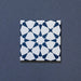 Close-up of Agraba Navy 20x20cm Moroccan-style ceramic tile featuring a bold geometric star pattern in deep navy blue and white on a textured dark background.