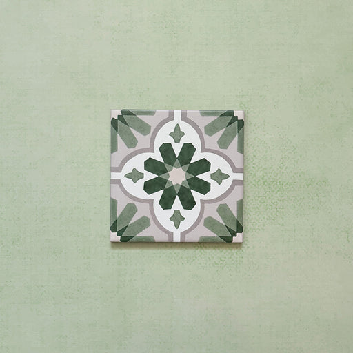 Flatlay featuring a single Clarence House Jade Mini 15x15cm Victorian Moroccan-style porcelain tile, showcasing a delicate green and white geometric floral pattern on a soft green background.