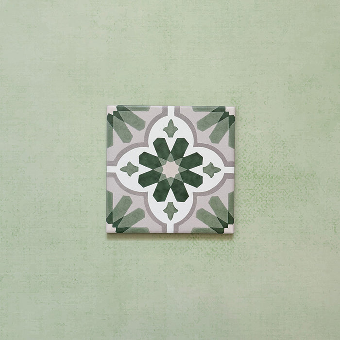 Flatlay featuring a single Clarence House Jade Mini 15x15cm Victorian Moroccan-style porcelain tile, showcasing a delicate green and white geometric floral pattern on a soft green background.