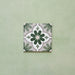 Flatlay featuring a single Clarence House Jade Mini 15x15cm Victorian Moroccan-style porcelain tile, showcasing a delicate green and white geometric floral pattern on a soft green background.