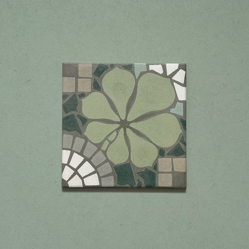 Single Bloom Green 20x20cm Moroccan-style ceramic tile featuring a floral pattern in soft green, grey, and white tones on a green background, shown in a product close-up.
