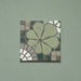 Single Bloom Green 20x20cm Moroccan-style ceramic tile featuring a floral pattern in soft green, grey, and white tones on a green background, shown in a product close-up.
